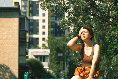 Image shows a woman sat outside experiencing heatstroke